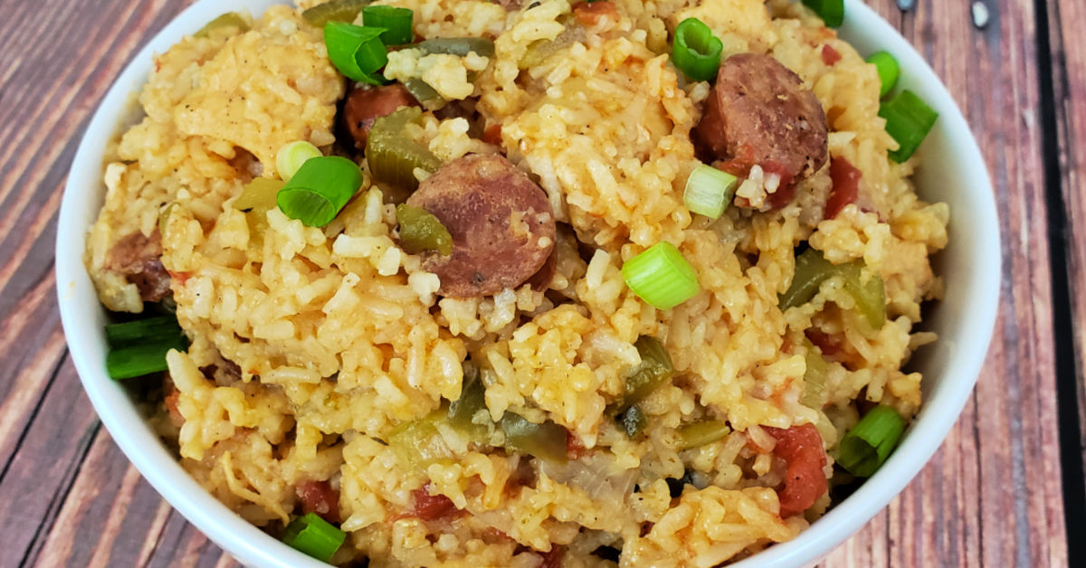 Chicken and sausage jambalaya served in white bowl and garnished with sliced green onions.