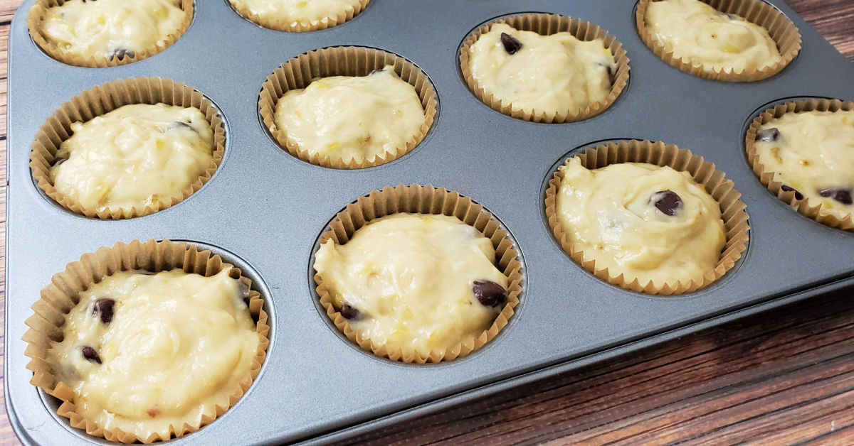 One third cup banana muffin batter scooped into 12 muffin liners in muffin tin.
