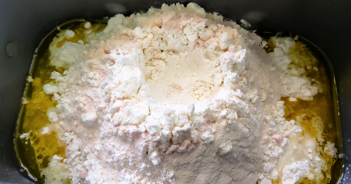 Flour, salt and xanthan gum piled in bread machine pan.