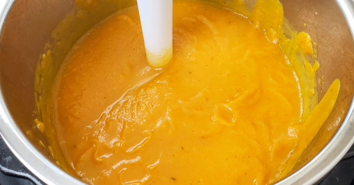 Butternut squash soup being pureed in the Instant Pot with an immersion blender.