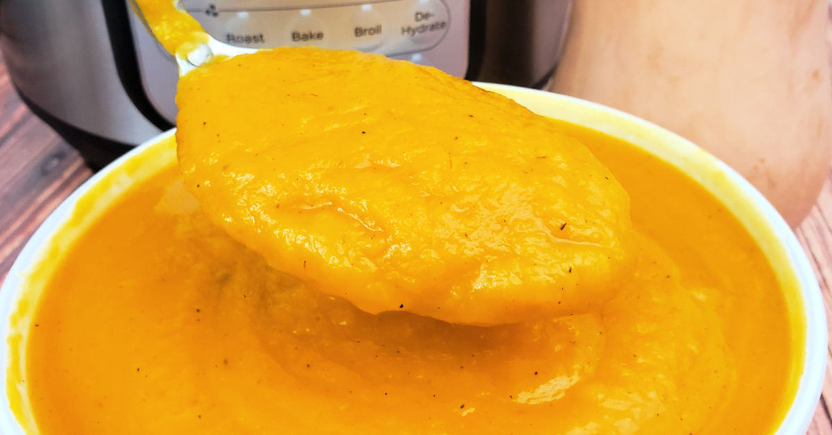 Butternut squash soup being served with a large spoon.