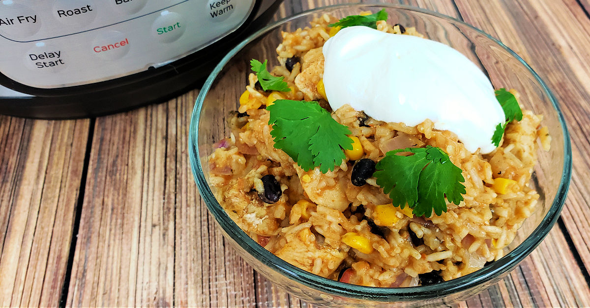 Chicken burrito bowl topped with sour cream and cilantro next to the Instant Pot it was cooked in.