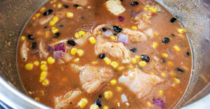 Chicken stock, salsa, corn and beans added to chicken and onion mixture in Instant Pot inner pan.