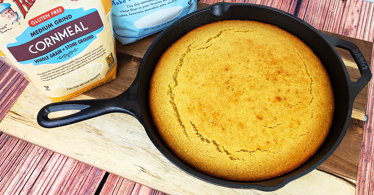 Baked gluten free cornbread skillet cooling on a cutting board.