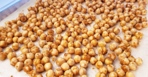 Seasoned chickpeas laid out on sheet pan.