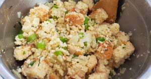 Gluten free stuffing mix being combined in a metal mixing bowl.