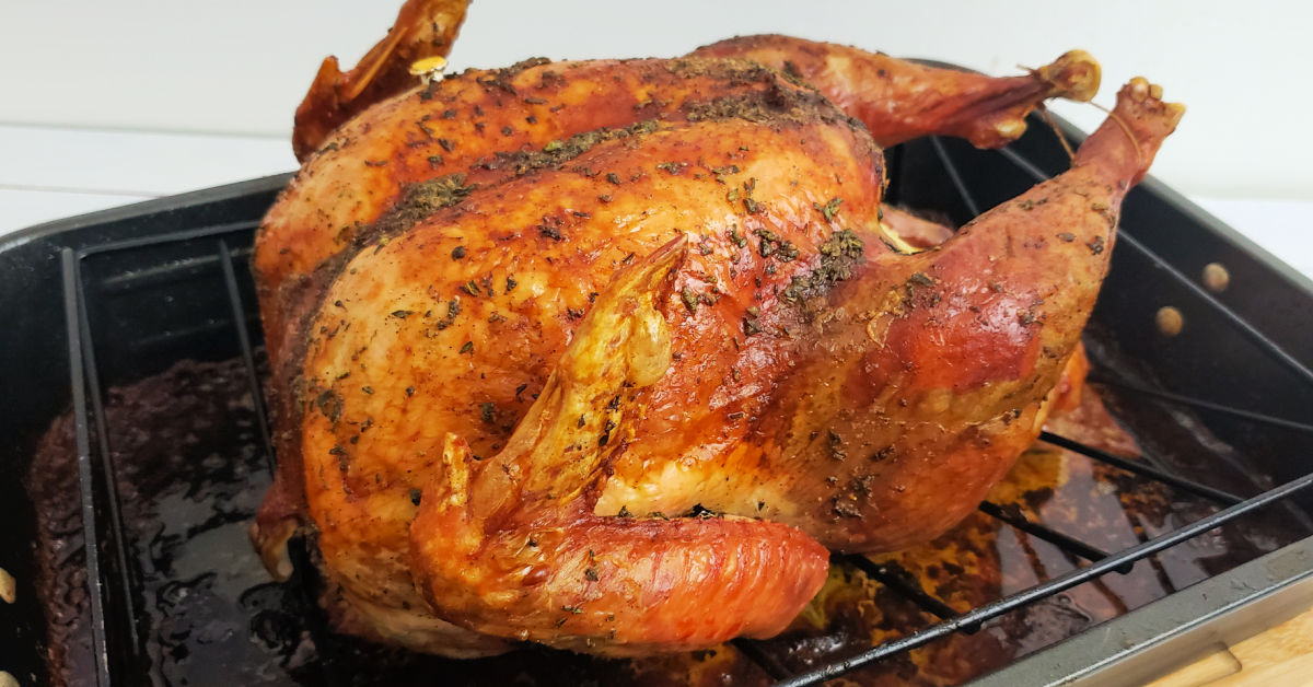 Herb roasted turkey on roasting pan.