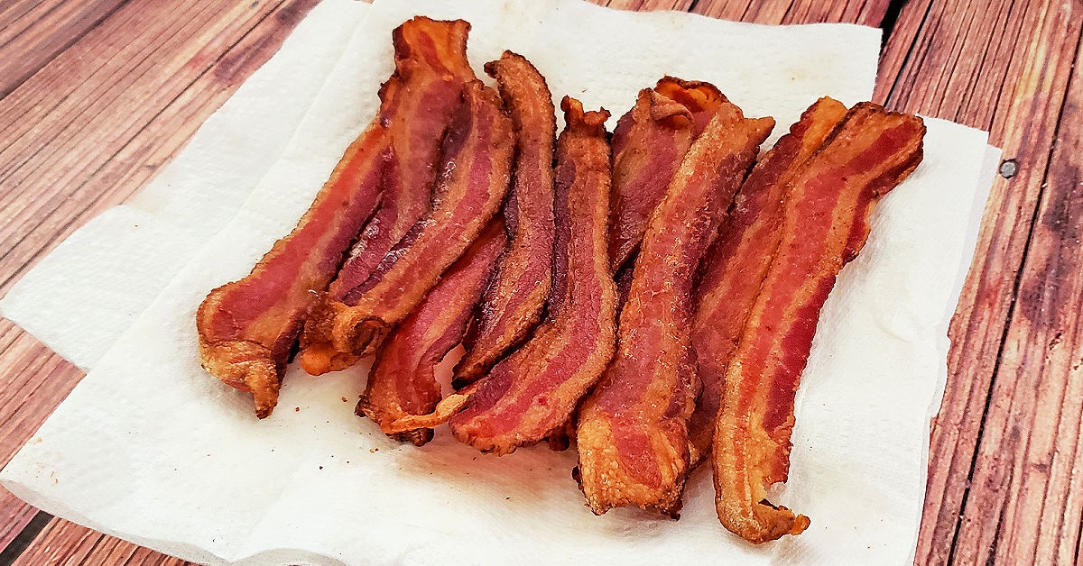 Air fried bacon draining on paper towel lined plate to remove excess grease.