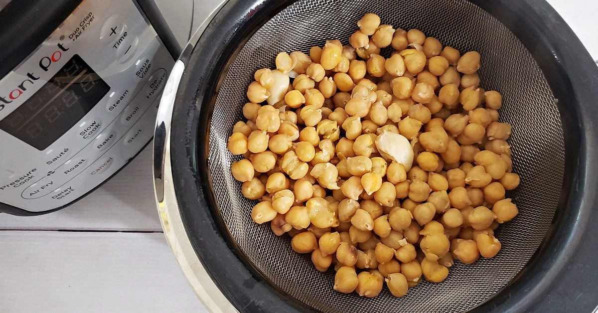 Strained chickpeas and garlic over bowl with Instant Pot.