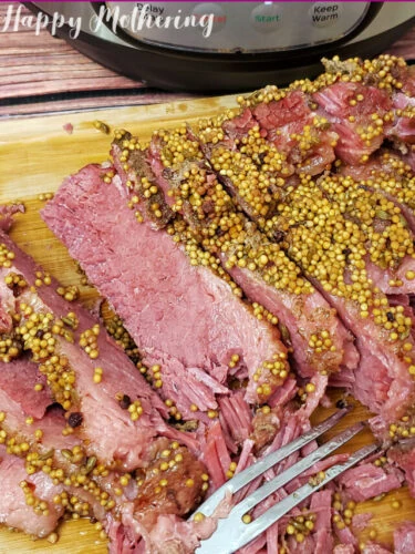 Sliced corned beef on cutting board next to Instant Pot.