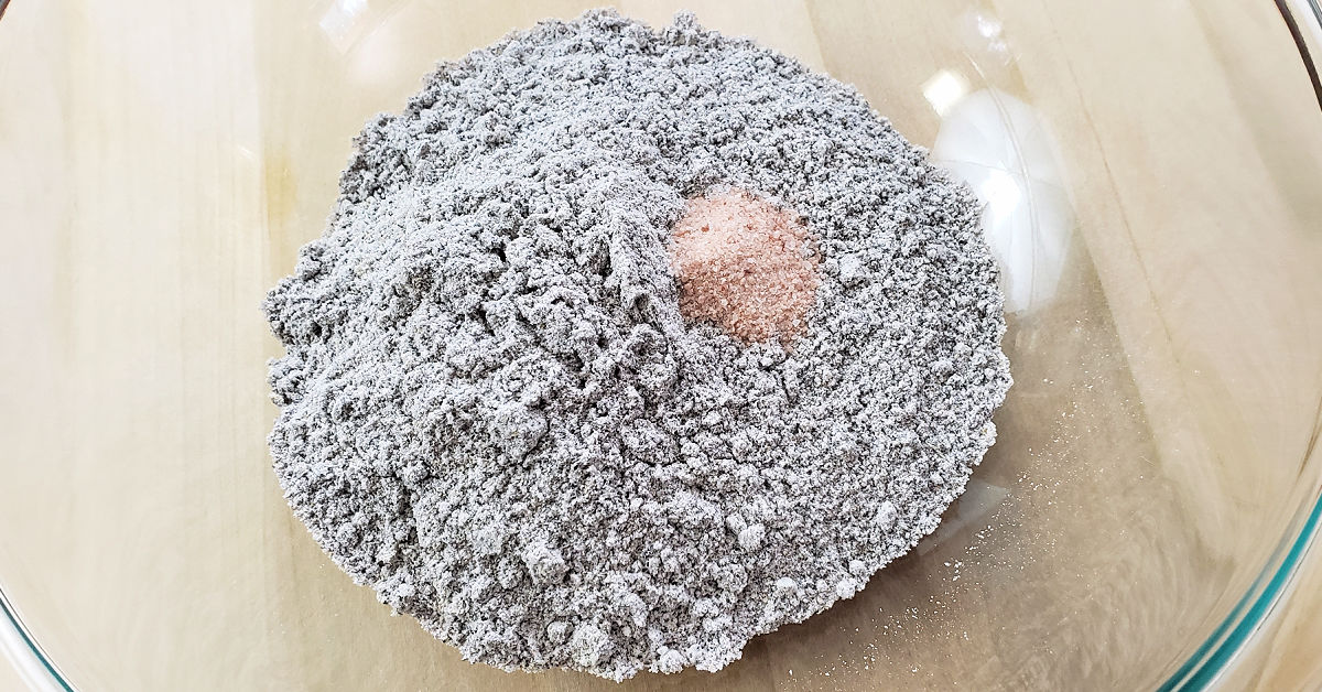 Blue corn flour and sea salt in a glass mixing bowl.