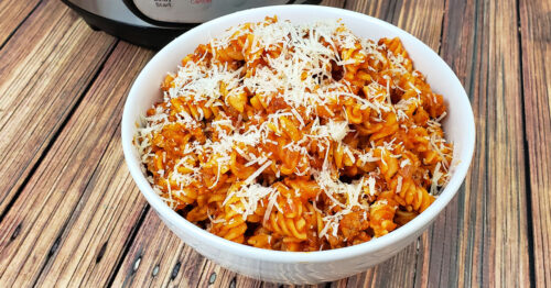 Bowl of gluten free pasta garnished with parmesan cheese.