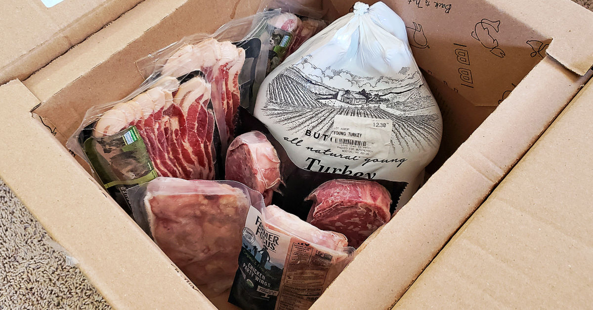Box of meat from ButcherBox, including 3 packs of bacon, 3 packs of chicken wings, 2 steaks and a whole turkey, shipped on dry ice.