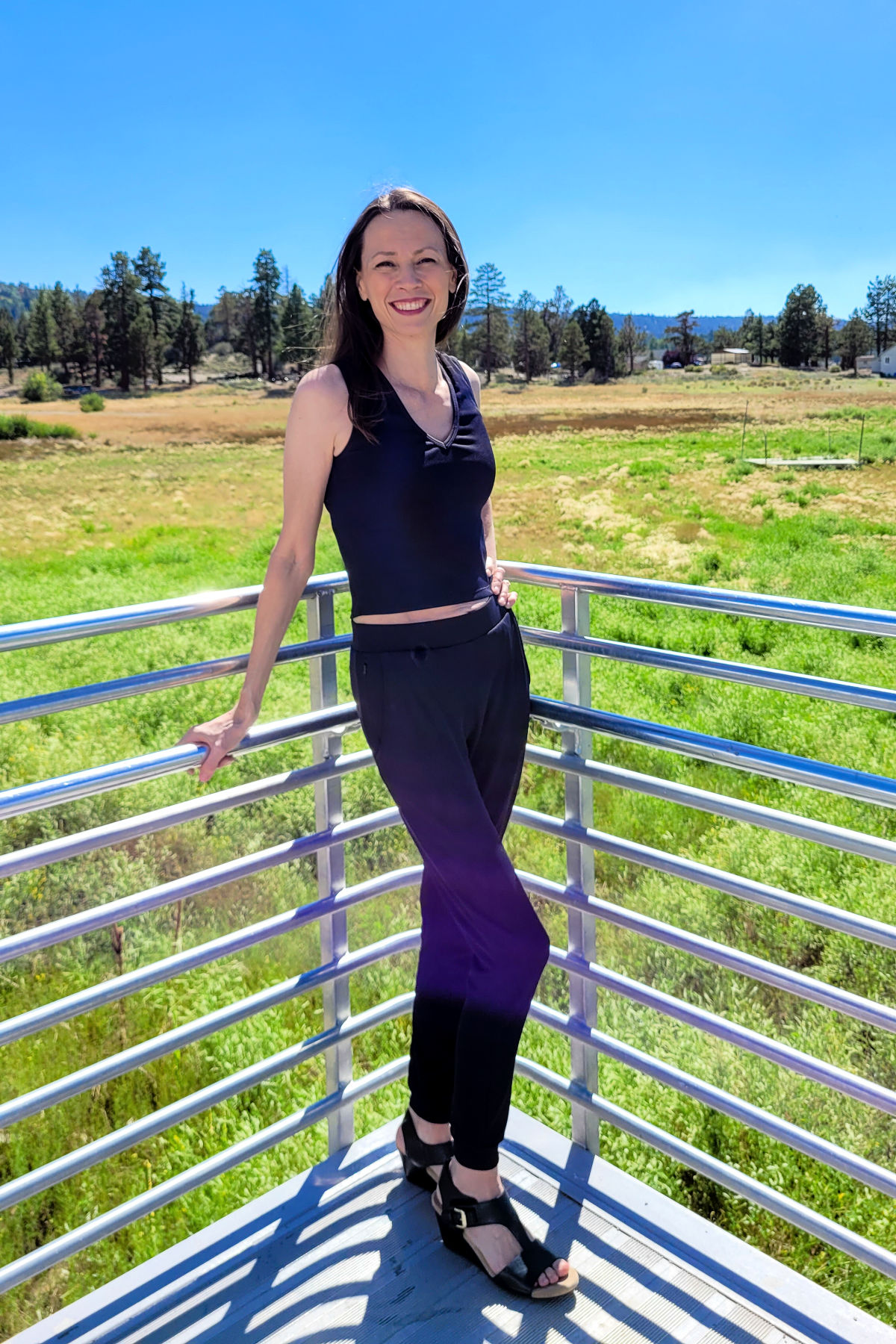 Chrystal wearing the Alina Tank and Eva Pant from Constant Sol with nature and blue skies in the background.