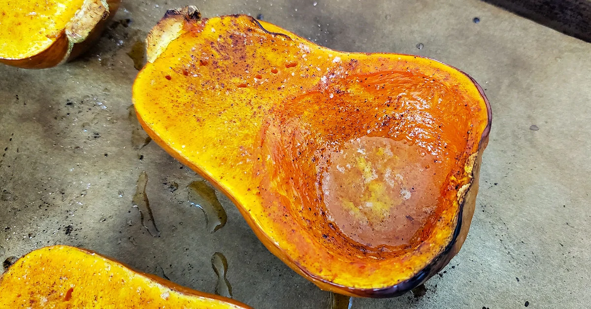 Roasted honeynut squash half on baking sheet after being removed from the oven.