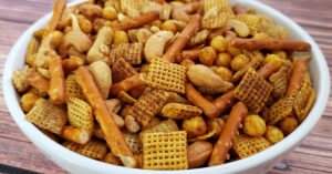 Bowl of homemade gluten free Chex mix on a wood table.
