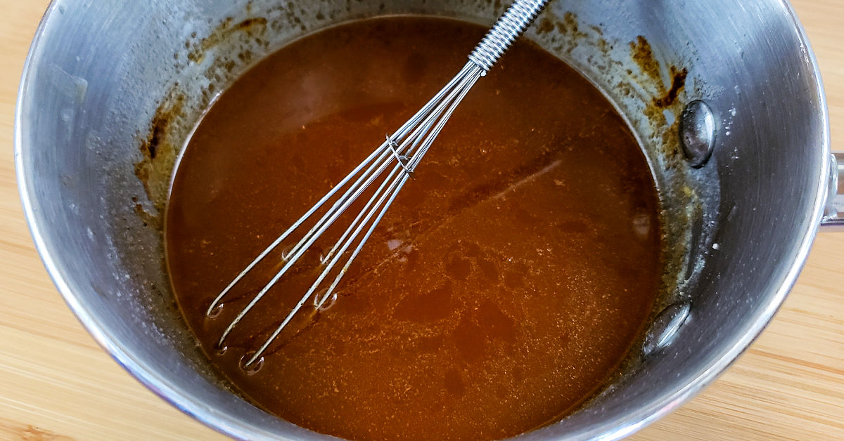Chex mix butter seasoning sauce being whisked together in saucepa.