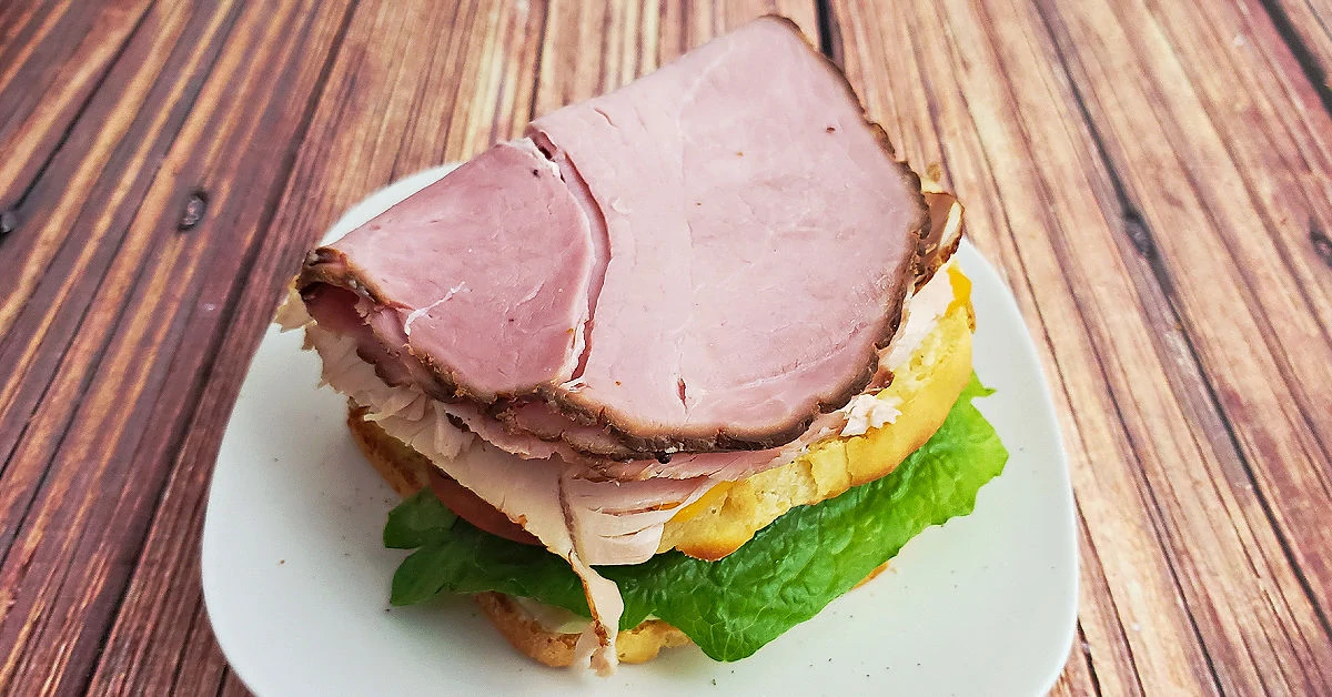Cheddar cheese, turkey and ham layered over slice of bread.