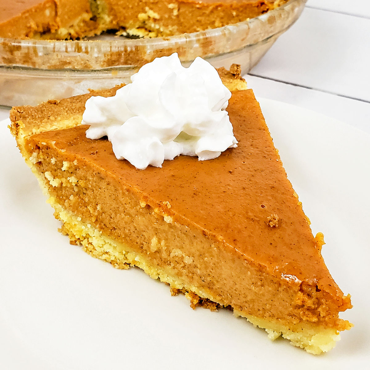 Slice of gluten free pumpkin pie served with whipped cream on top.