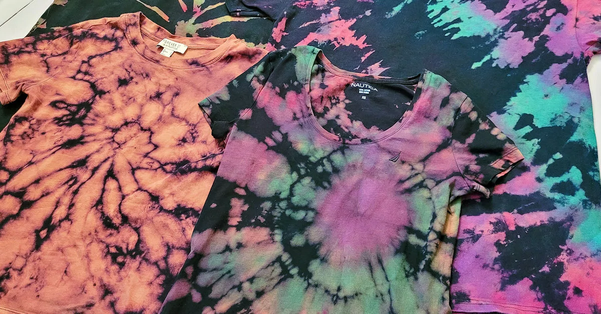 Four different reverse tie dye shirts laid out on a table.