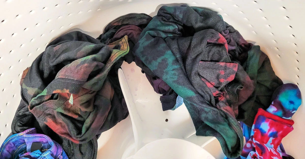 Reverse tie dye t-shirts in washing machine to be washed.