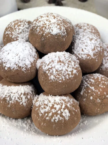 Pile of chocolate truffles sprinkled with powdered sugar.