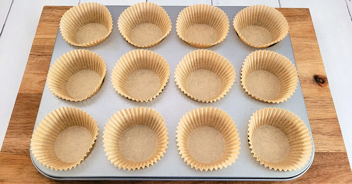 Muffin pan lined with 12 brown paper liners.