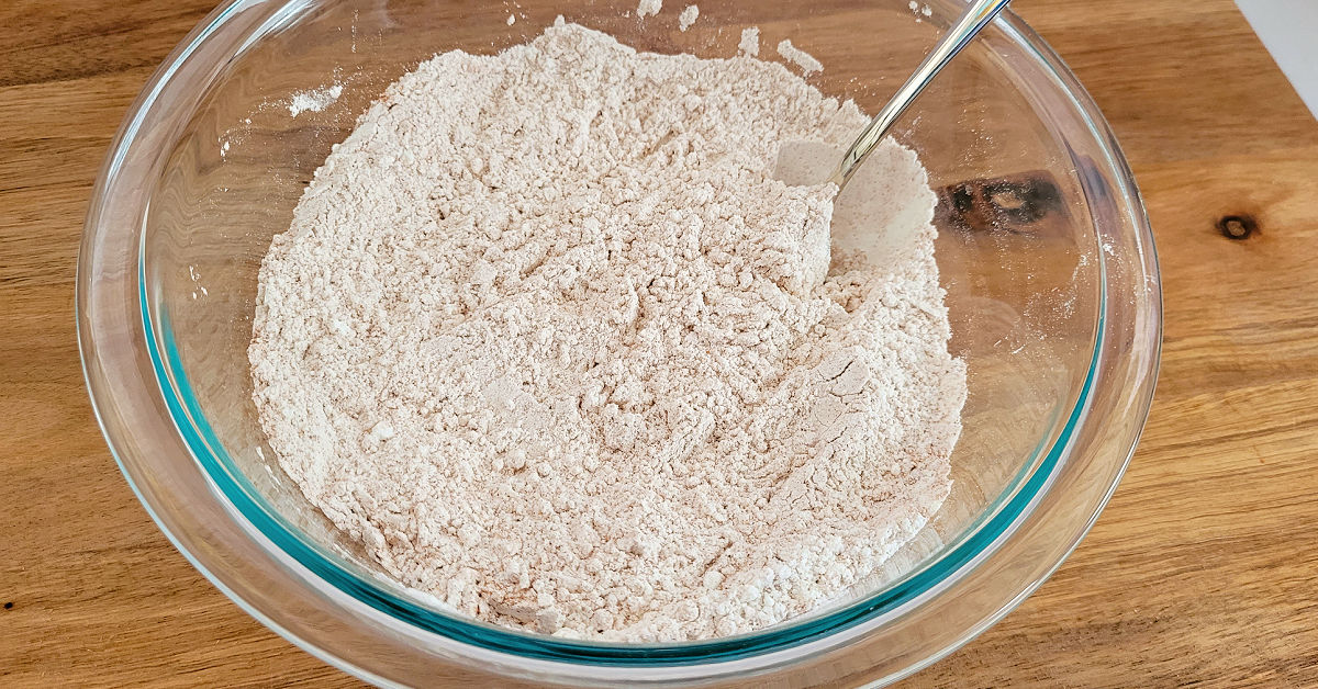 Gluten free flour mixture being stirred in a glass mixing bowl.