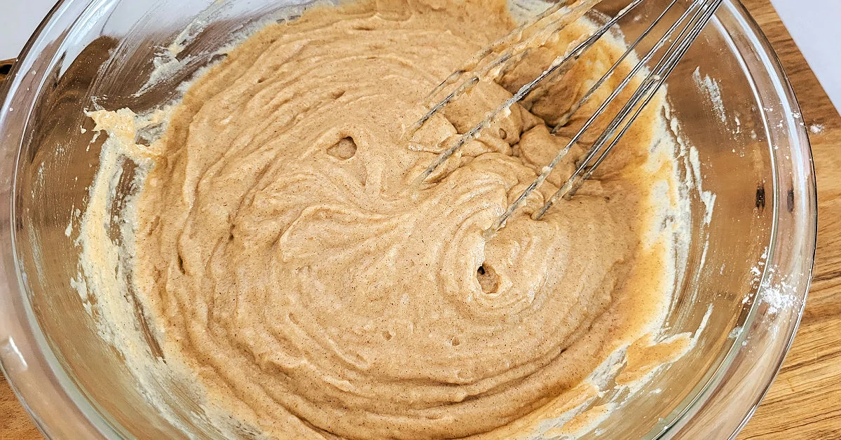 Gluten free apple muffin batter being whisked together in mixing bowl.