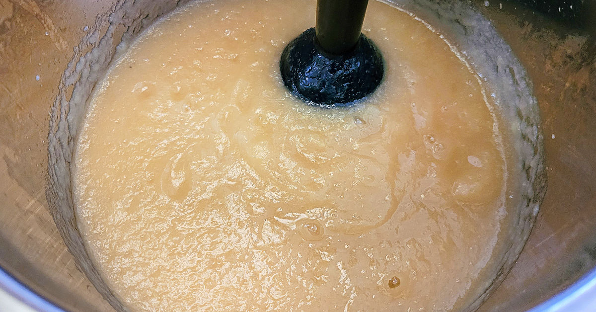 Instant Pot applesauce being blended with an immersion blender to be smooth.