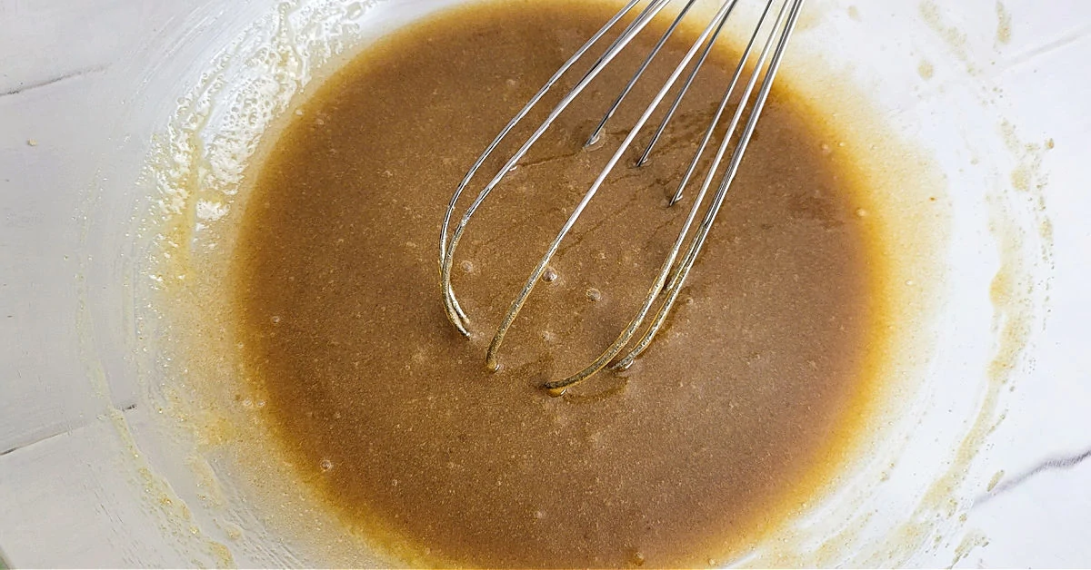 Milk, vanilla and butter whisked together with brown and white sugars in a large glass mixing bowl.