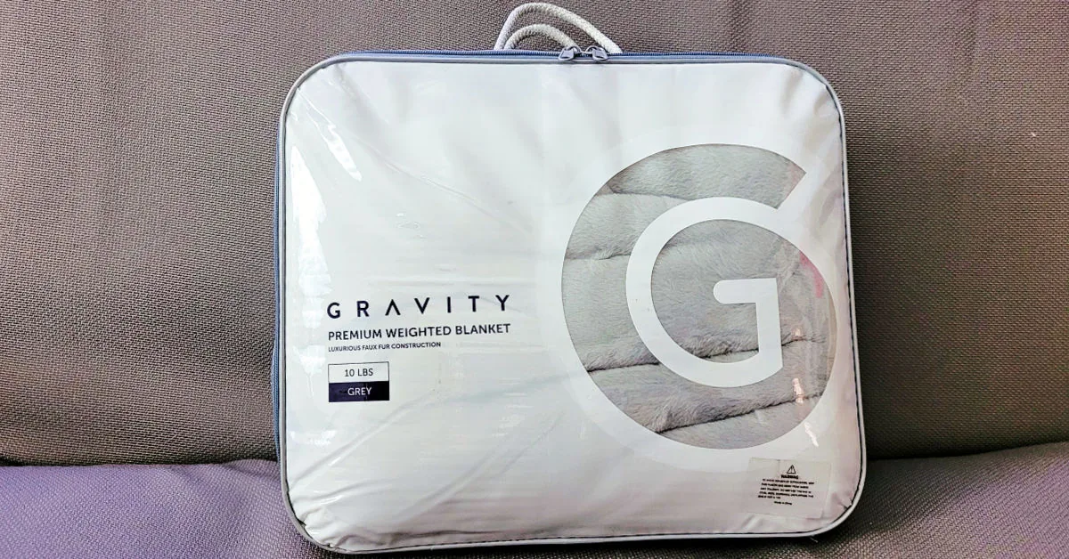 Gravity weighted blanket in its reusable packaging on the futon.