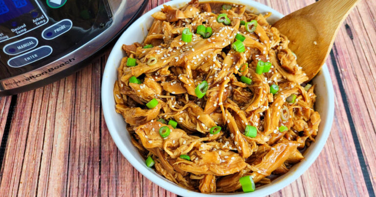 Teriyaki Chicken served in a white bowl with a bamboo spoon, which is set next to a slow cooker.