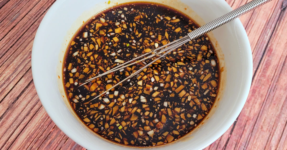Homemade teriyaki sauce in a small white bowl with a whisk.