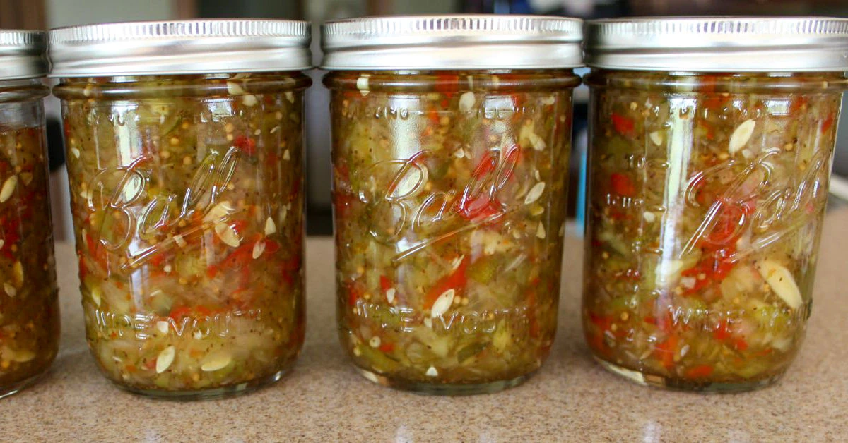 3 jars of homemade pickle relish canned in mason jars sitting on a counter.